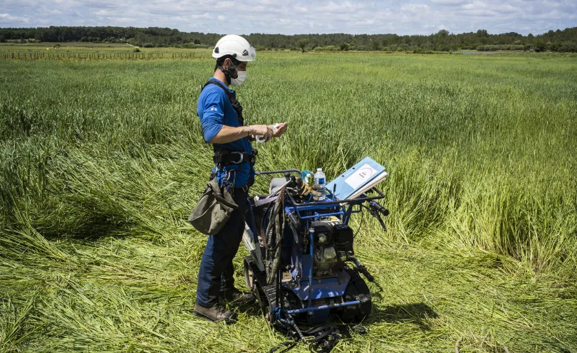 Photo d'un technicien portant un masque de protection respiratoire et en train de se désinfecter les mains avec du gel hydroalcoolique