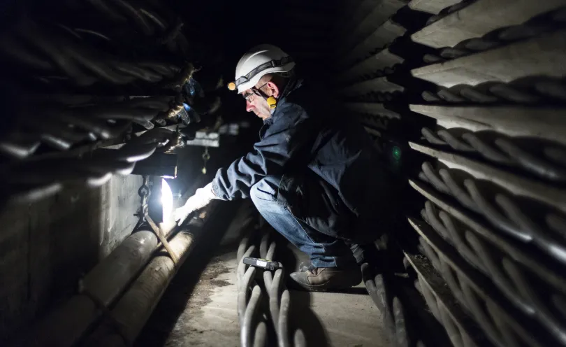 Photo d'un technicien dans une galerie souterraine et éclairé par une lampe