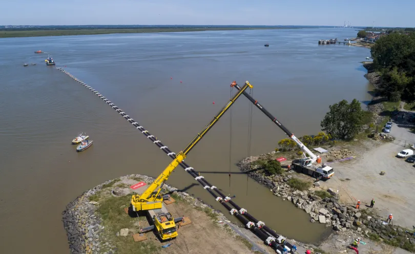 Photo des deux grues soulevant les fourreaux sur la plage