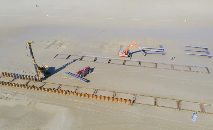 Photo aérienne d'engins de chantier en train de creuser des tranchées sur la plage