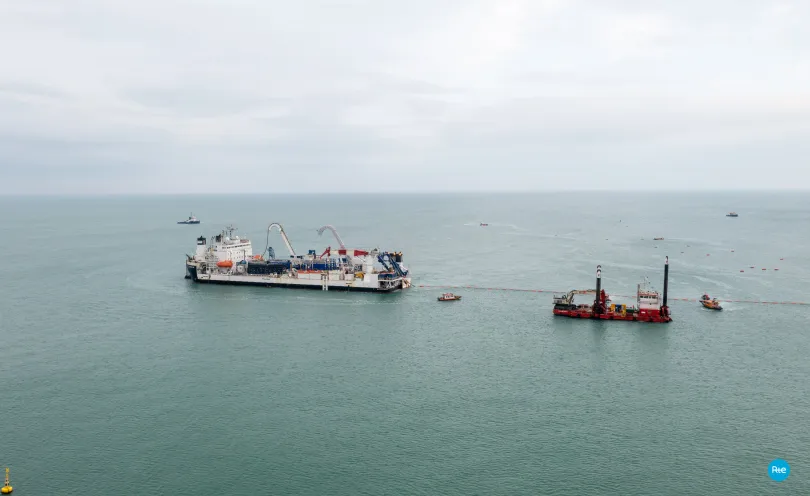 Photo d'un navire câblier en train dérouler un câble en mer, flottant à l'aide de bouées