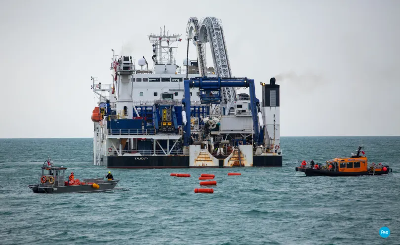 Photo zoomée de l'arrière du navire câblier ainsi que des bateaux d'intervention