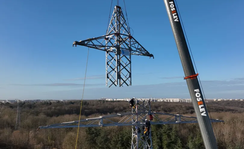 Photo d'une tête de pylône transportée par une grue