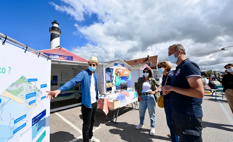 Photo de personnes devant un panneau d'informations au village des énergies du futur