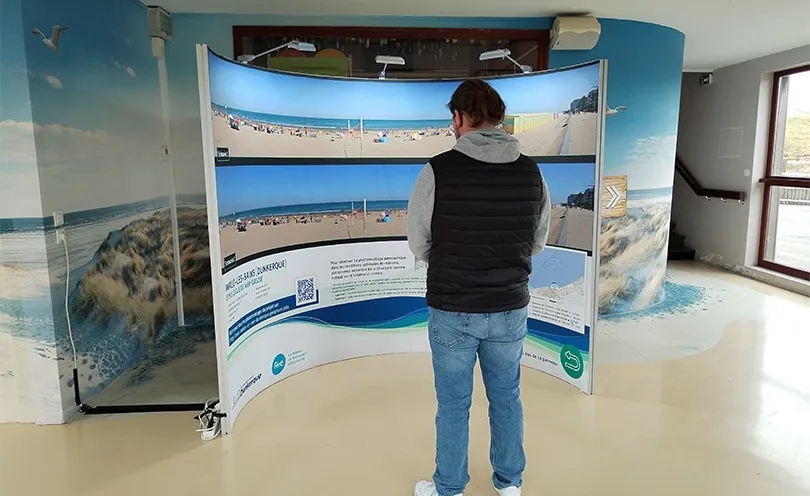 Photo d'une personne en train de lire le panneau d'informations du projet éolien en mer de Dunkerque