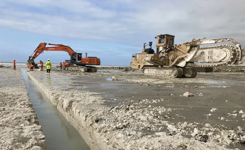 Photo d'un engin de chantier en train de creuser une tranchée sur une plage