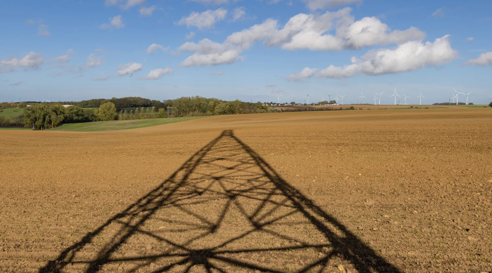 Ombre d'un pylone électrique sur un champs de terre