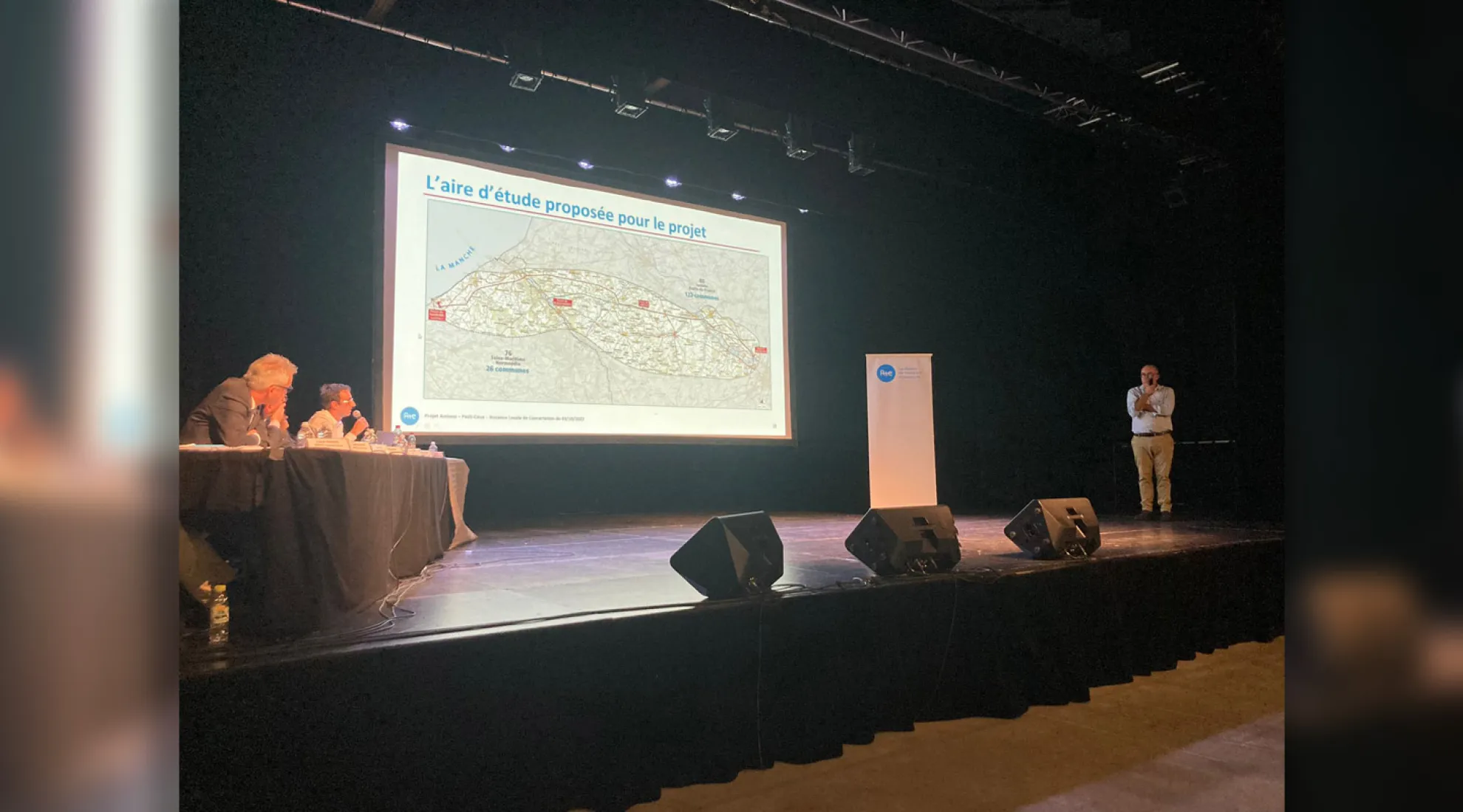 3 personnes sur scène présentant une carte