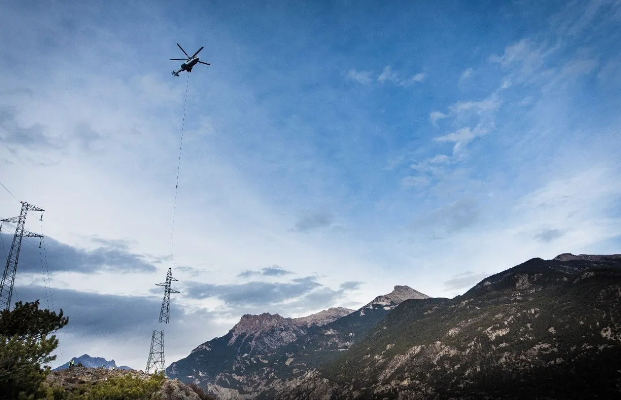 Photo de la partie supérieure d'un pylône transportée par un hélicoptère