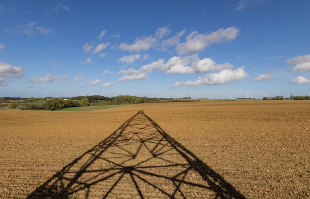 Ombre d'un pylone électrique dans un champ de terre